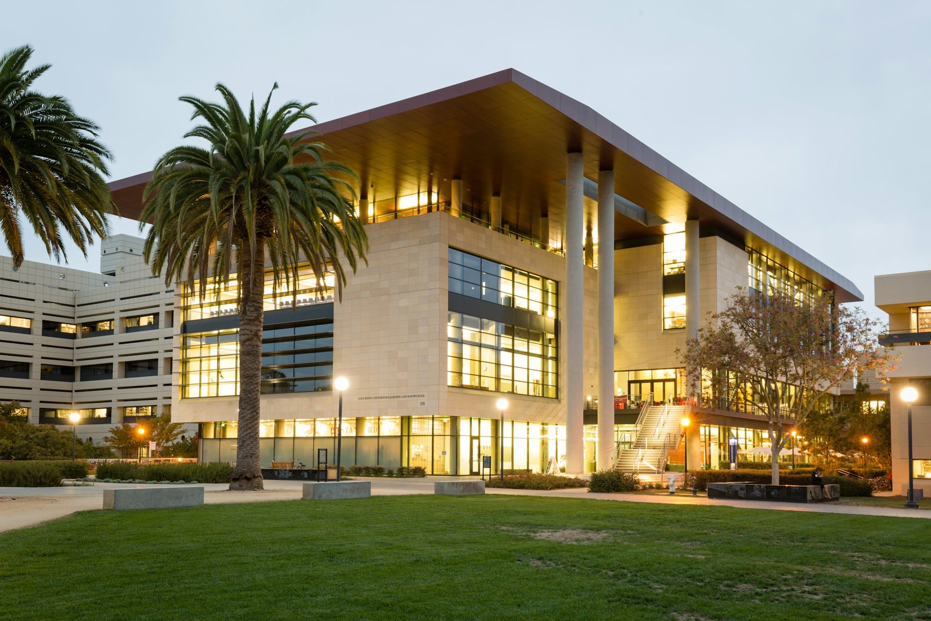 A photo of a large building near palm trees and a lawn of grass